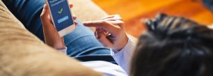 a woman sitting on a couch holding a smart phone.